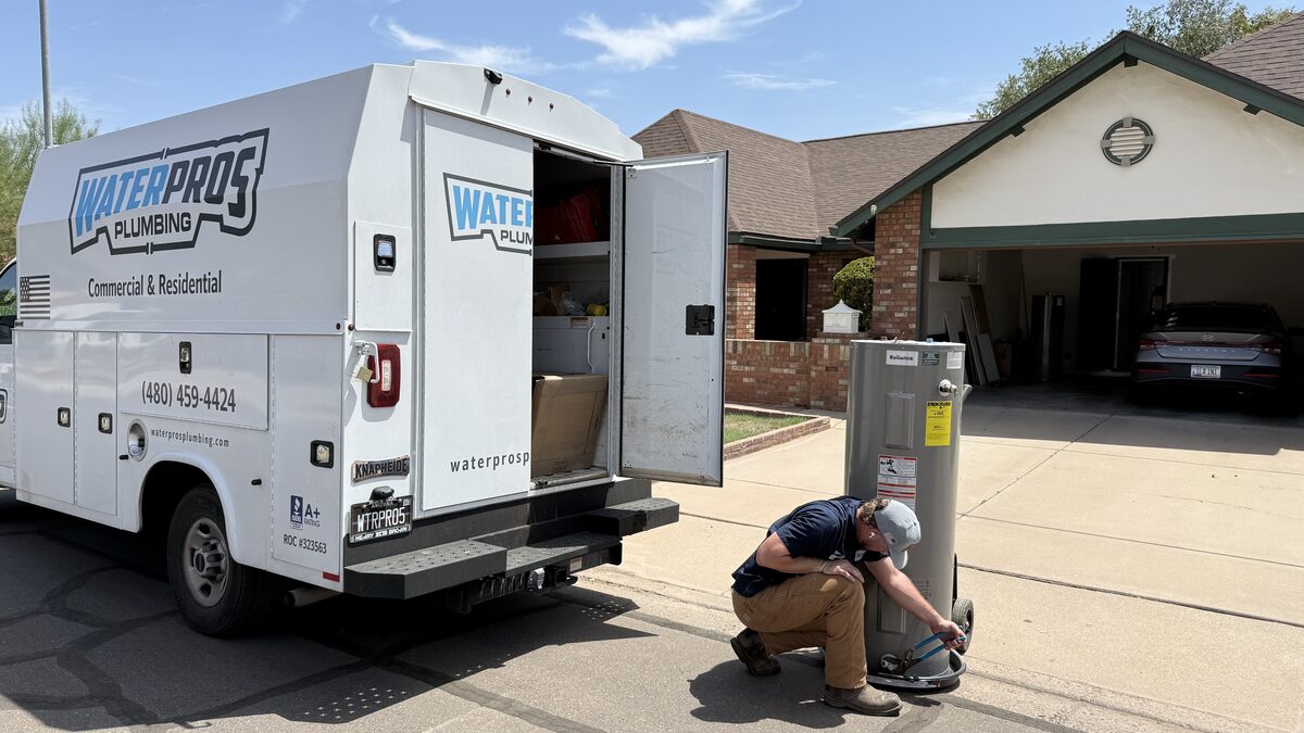 Water Pros Plumbing technician removing a leaking 50-gallon electric water heater from a Dobson Ranch home in Mesa AZ